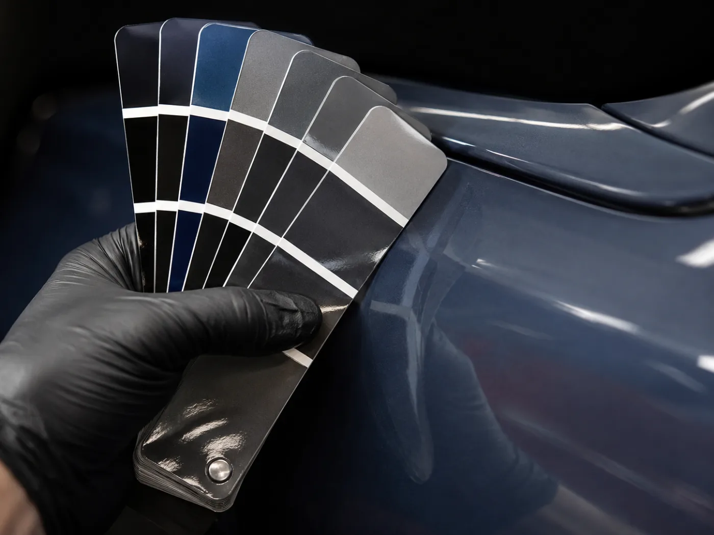 Igualación de color con abanico de muestras de pintura sobre una carrocería azul